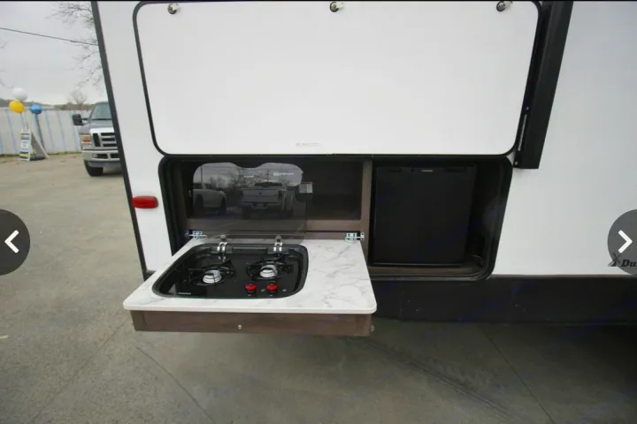 RV rental: Exterior view of an RV's outdoor kitchen, showing a two-burner stove, sink, and mini-fridge.. Dutchmen Coleman Light 2020