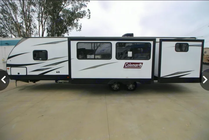 Side view of a white Coleman travel trailer (RV) with an extended slide-out, ideal for RV rental.. Dutchmen Coleman Light 2020