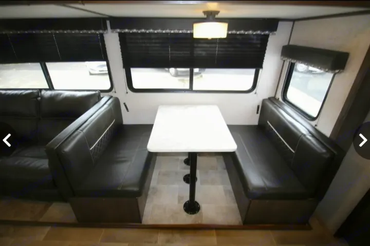 RV rental: Cozy dinette with black benches & white table, plus a comfy sofa for travel. Ideal living space setup.. Dutchmen Coleman Light 2020