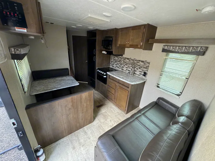 RV rental's inviting interior: kitchen with backsplash, dining booth, and sofa create a functional living space.. Dutchmen Aspen Trail 2020