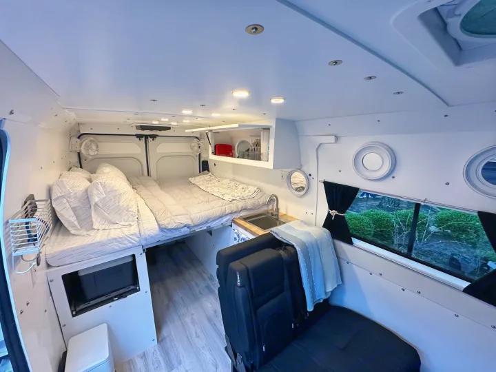 Spacious RV rental interior featuring a cozy bed, compact kitchen, and versatile seating for comfortable mobile living.. RAM PROMASTER 2500 2023