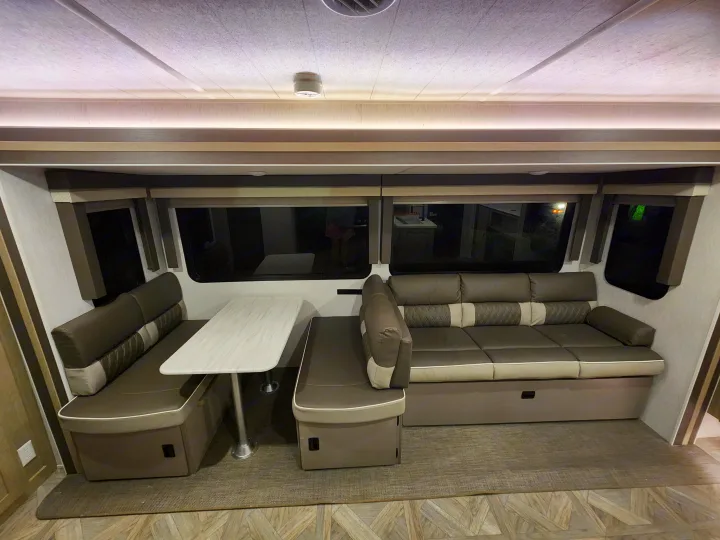 RV rental living area featuring comfortable dinette seating and a large sectional sofa.. Forest River Wildwood 2023