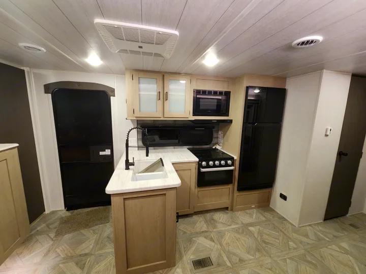 This RV rental's modern kitchen boasts a fridge, stove, microwave, and sink, offering comfortable living on the road.. Forest River Wildwood 2023