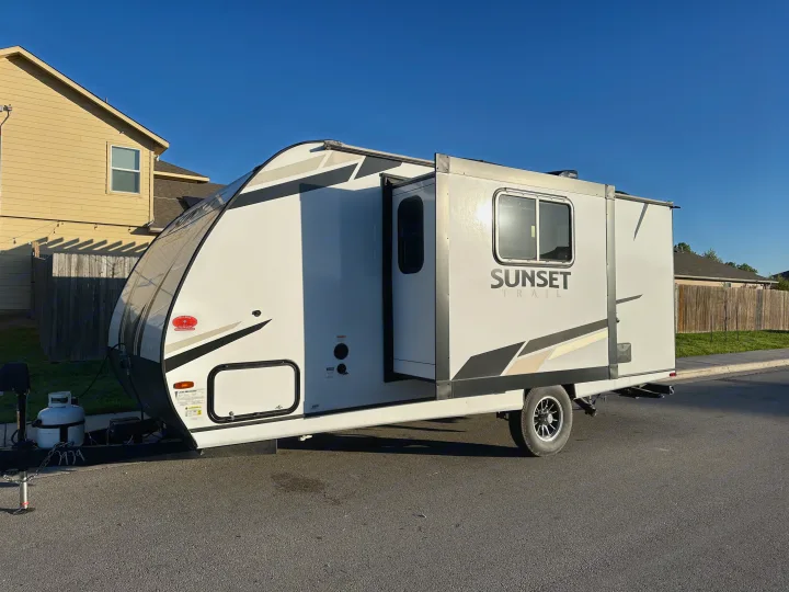 White RV rental, a Sunset Trail travel trailer, parked outside with its slide-out extended, ready for adventure.. Crossroads RV Sunset Trail Super Lite 2022