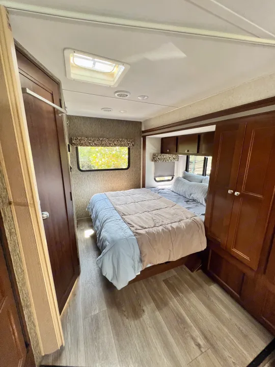 Cozy RV rental bedroom with warm wood tones, a comfortable bed, and natural light from windows and a skylight.. Forester GTS 2018