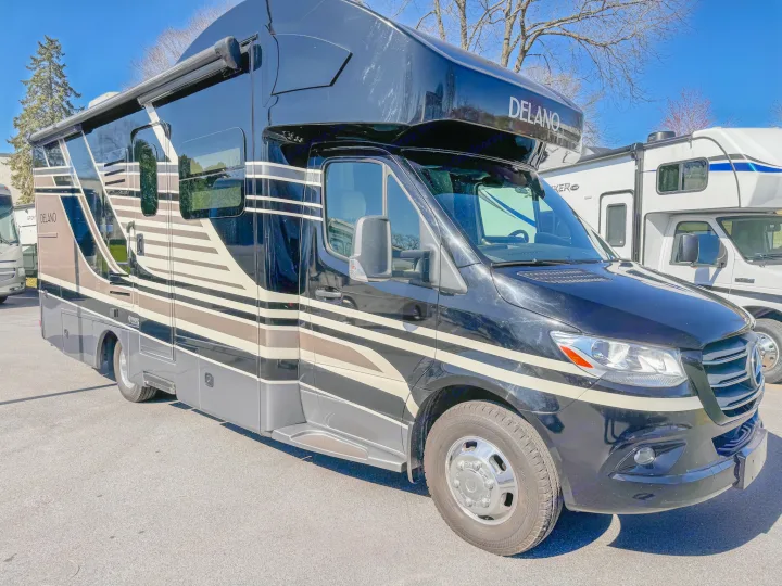 Striking black and beige Delano RV rental, a modern touring motorhome parked on asphalt. Ready for adventure.. Thor Motor Coach Delano 2022