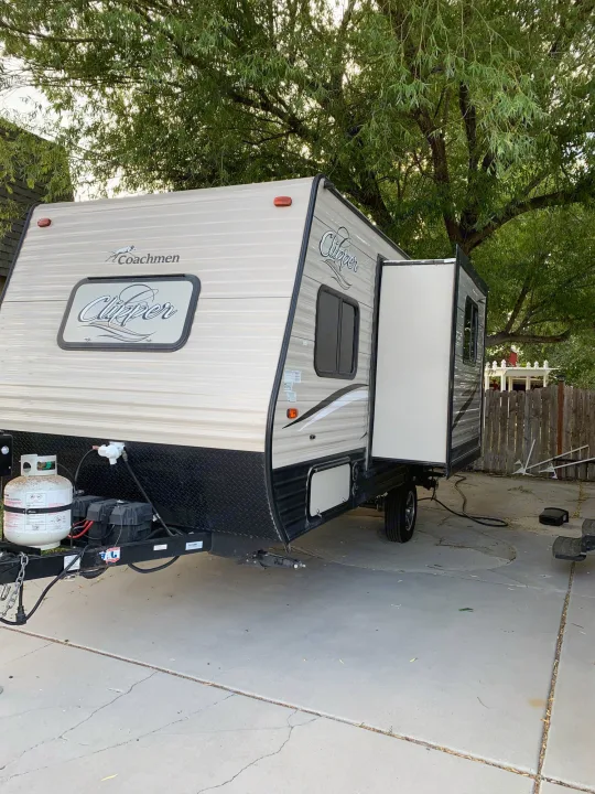 Light-colored Coachmen Clipper travel trailer with a side pop-out, ideal for rv rental. Parked on concrete driveway.. Coachmen Clipper 2017