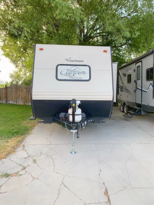 Front view of a Coachmen Clipper travel trailer, ready for rv rental, parked next to another RV on a cracked driveway.. Coachmen Clipper 2017