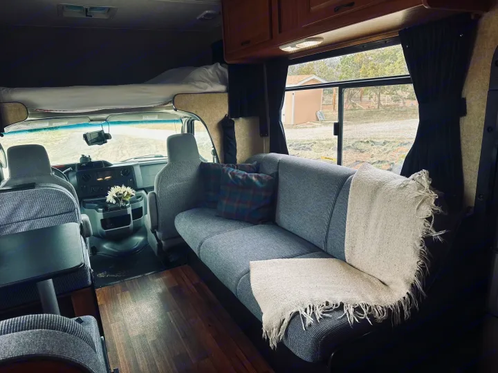 Step inside this inviting RV rental, featuring a spacious sofa, bed above the cab, and a functional interior for your next adventure.. Thor Majestic 2016