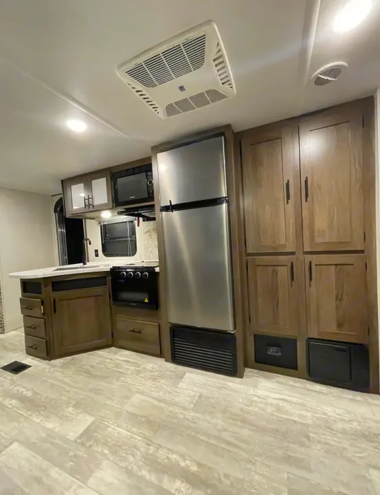 RV rental kitchen: modern stainless steel appliances, light wood cabinets, and durable flooring for comfortable travel.. Forest River PRIME TIME AVENGER 2021