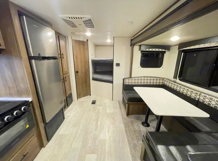 Spacious RV rental interior featuring a kitchen, large fridge, bunk beds, and a comfortable U-shaped dinette.. Forest River PRIME TIME AVENGER 2021