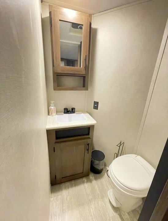 Explore this clean, compact rv rental bathroom, featuring a sink vanity, mirrored cabinet, and toilet.. Forest River PRIME TIME AVENGER 2021