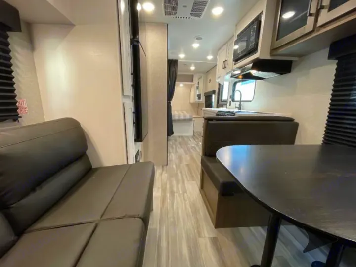 Spacious RV rental interior featuring a lounge, kitchen with microwave, dining booth, and rear bedroom.. Jayco Jay Flight 2024
