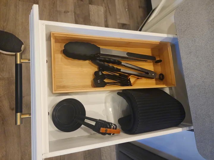 Organized RV rental drawer: kitchen tongs, measuring spoons/cups, and a roll-up rack, optimizing compact space.. Entegra Coach Odyssey 2021