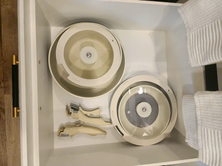 RV rental kitchenware: Drawer shows nesting pots with clear lids, removable handles, and folded white towels for efficient storage.. Entegra Coach Odyssey 2021