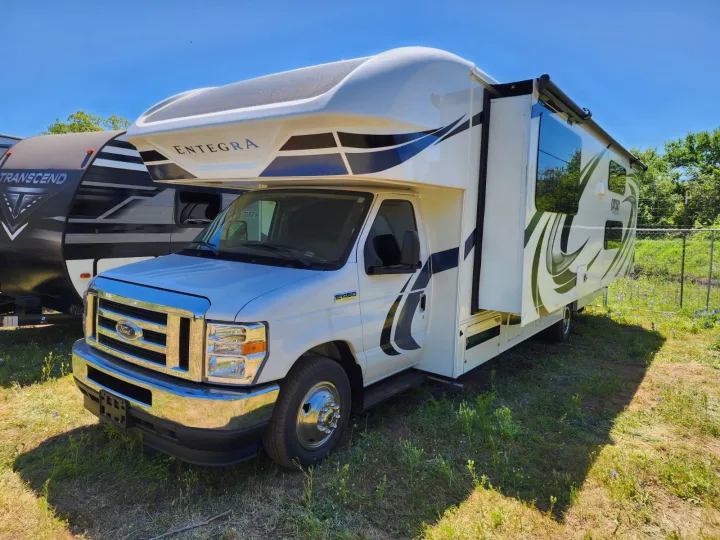 A white Entegra Class C RV (Ford E350) with extended slide, black & olive graphics, parked on grass for rv rental.. Entegra Coach Odyssey 2021