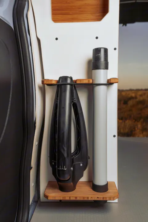 Organized rv rental interior with custom storage for outdoor gear, including a collapsible tool and a pole, secured on a bamboo rack.. Renault Trafic 2025