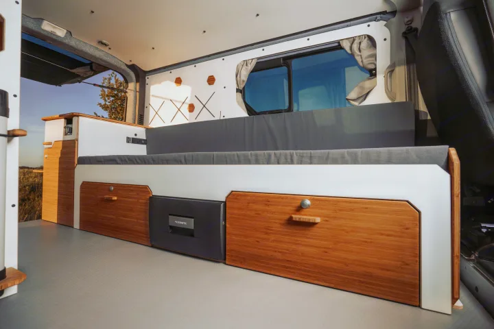 Modern rv rental interior featuring a Dometic fridge, bamboo storage drawers, and comfortable gray bench cushions.. Renault Trafic 2025