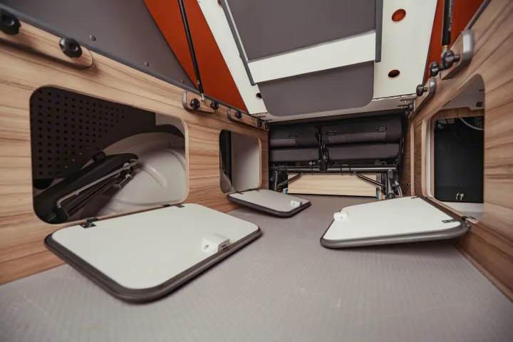 RV rental: interior view showing underfloor storage compartments open next to a folded bed/seating area.. Volkswagen Transporter T6.1 2022