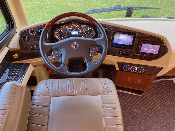 Driver's cockpit of an RV rental: luxurious dashboard with steering wheel, analog gauges, and infotainment screens.. Tiffin Motorhomes Allegro Bus 2017