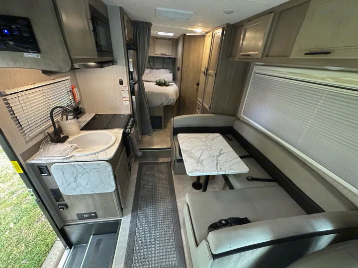 View inside a well-appointed rv rental showing the kitchen, dining booth, and bedroom area.. Coachmen Other 2022