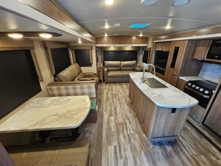 Spacious rv rental interior: living room with recliners, dining booth, and full kitchen.. Grand Design Imagine 2021