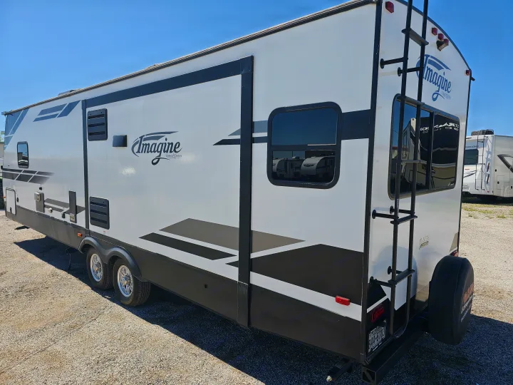 White Imagine RV rental, a sleek travel trailer with a rear ladder and spare tire, ready for your camping trip.. Grand Design Imagine 2021