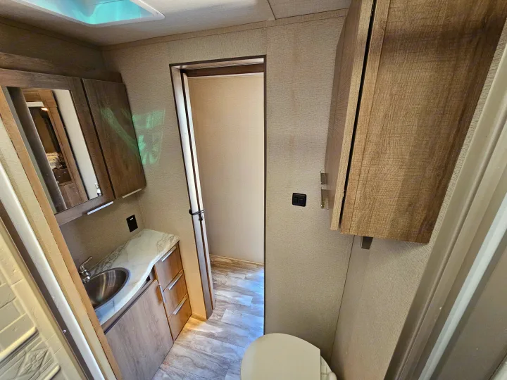 Step inside this RV rental's bright bathroom, complete with a modern sink, vanity, mirrored cabinet, toilet, and shower stall.. Grand Design Imagine 2021