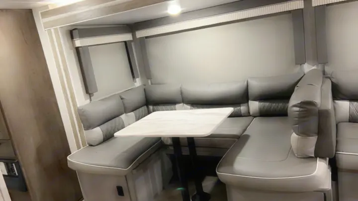 Modern gray U-shaped dinette with a table in a clean RV rental, ideal for dining and lounging.. Forest River Wildwood X-Lite 2021