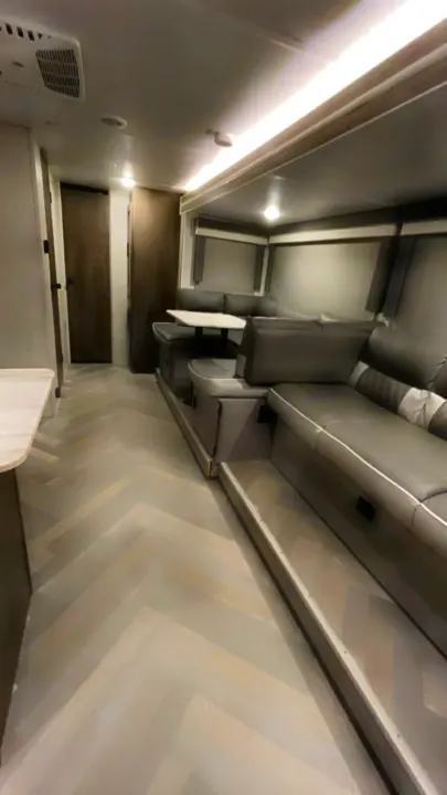 This bright RV rental showcases a modern gray living area with comfy dinette & sofa, plus sleek herringbone floors.. Forest River Wildwood X-Lite 2021