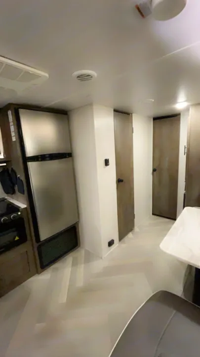 Inside an RV rental: modern kitchen appliances, a light-filled hallway with doors, and herringbone flooring for a comfortable stay.. Forest River Wildwood X-Lite 2021