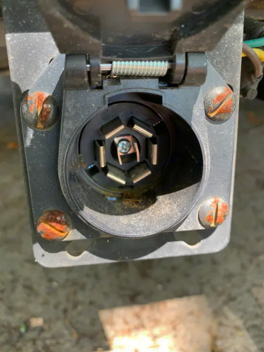Close-up of a rusty 7-pin trailer connector on a vehicle, essential for rv rental towing.. nuCamp T@G 2022