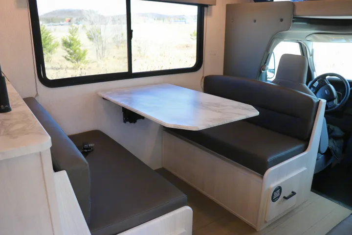 RV rental dinette with modern table, comfortable booth seating, and storage drawers.. East to West entrada 2025