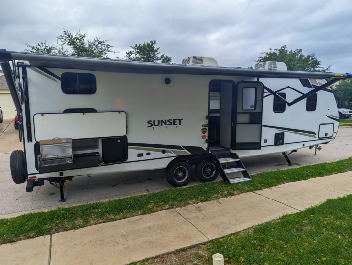 RV rental: A white Sunset Trail travel trailer with awning deployed, steps down, and outdoor kitchen setup.. Crossroads RV Sunset Trail Superlite 2024