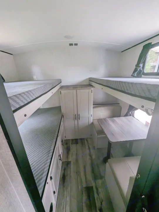 Inside an RV rental, showing a cozy dinette, ample storage, and comfortable bunk beds, ideal for families traveling.. Crossroads RV Sunset Trail Superlite 2024