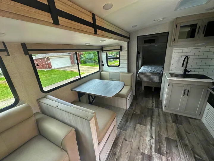 Spacious, modern RV rental interior with light wood accents, featuring a dinette, kitchen, and living area.. Crossroads RV Sunset Trail Superlite 2024