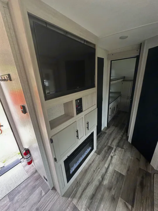 Spacious RV rental interior featuring a TV, electric fireplace, and a bunkhouse section for comfort.. Crossroads RV Sunset Trail Superlite 2024
