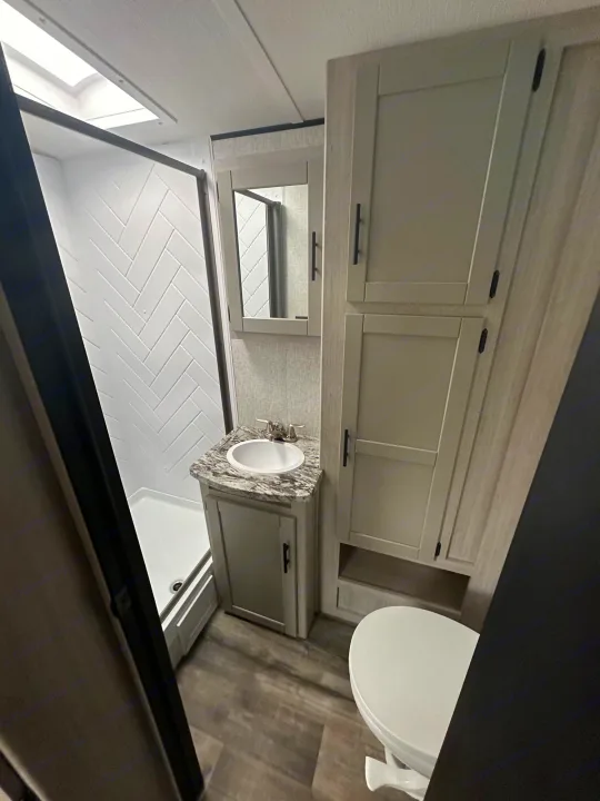Spacious RV rental bathroom featuring a modern shower, vanity with sink, toilet, and ample storage cabinets for your travels.. Crossroads RV Sunset Trail Superlite 2024