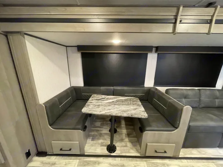 Spacious RV rental interior featuring a comfy U-shaped dinette with a modern table and extra seating.. Keystone Kodiak 2022