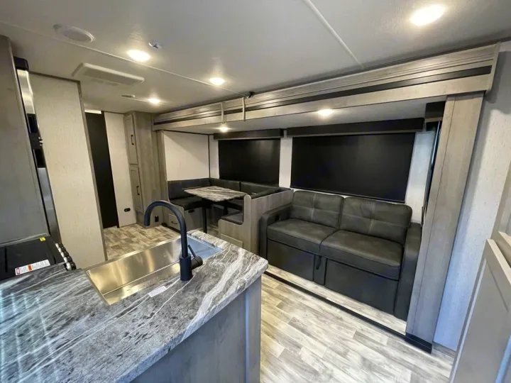 Modern rv rental interior with kitchen sink, comfy sofa, and dinette booth. Ready for your next travel trailer adventure!. Keystone Kodiak 2022