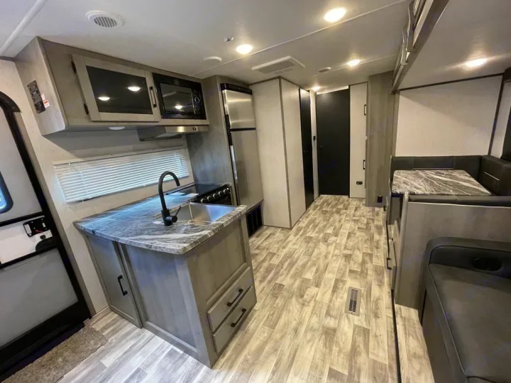 Spacious RV rental interior featuring a full kitchen and comfy dining/lounge space.. Keystone Kodiak 2022