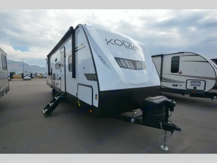 White travel trailer RV rental, steps down, parked outdoors with mountains beyond. Great recreational vehicle.. Keystone Kodiak 2022