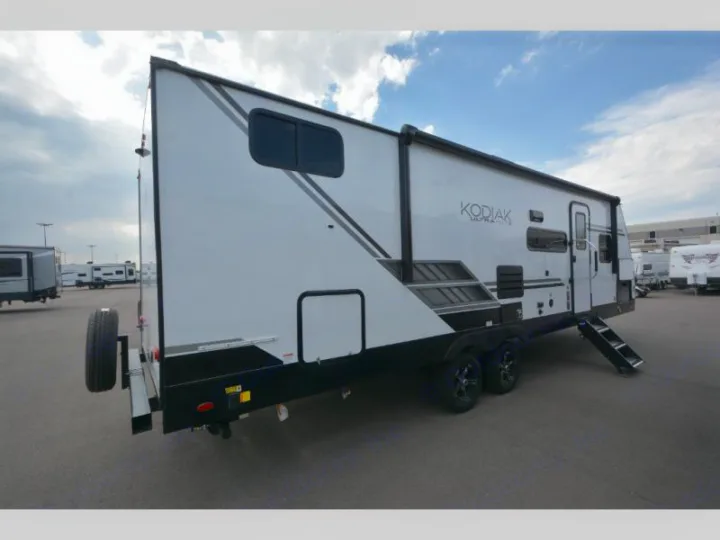 A white Kodiak travel trailer, perfect for RV rental and outdoor adventures. Side view, spare tire visible.. Keystone Kodiak 2022