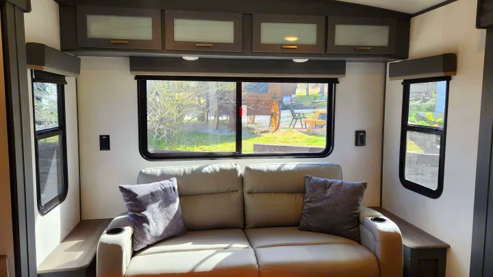 Relax in this bright RV rental! Features a comfortable sofa, large windows with outdoor views, and stylish overhead cabinets.. Keystone RV Bullet Premier Ultra Lite 2022