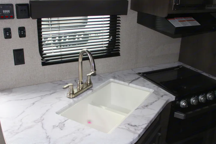 RV rental kitchen: This image shows a well-equipped interior with marble-look counters, a sink, stove, and utility controls.. Jayco Jayflight SLX 8 2021