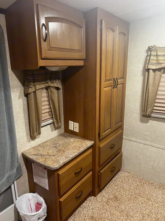 RV rental interior: wood cabinets, tall wardrobe, counter, window with blinds. Cozy and functional compact space.. Keystone RV Outback Toy Hauler 2013