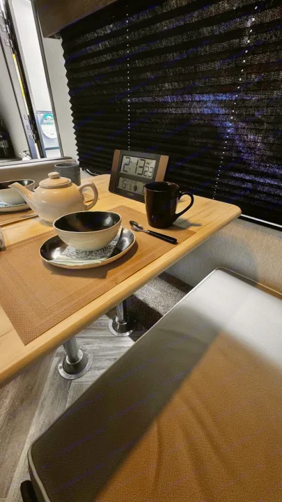Cozy RV rental interior with a dining table, tea set, digital clock (2:13 PM), and black window blinds.. Forest River Salem 2022