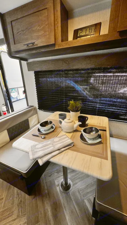 This rv rental features a compact, functional dinette with a set table, bench seating, and dark window blinds.. Forest River Salem 2022