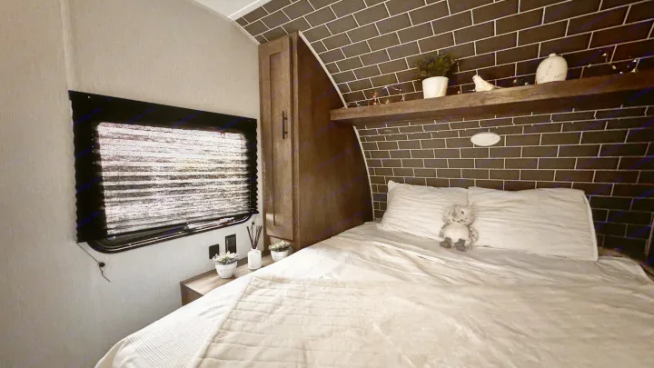 Cozy RV rental bedroom with white bedding, window, and stylish brick-patterned accent wall.. Forest River Salem 2022