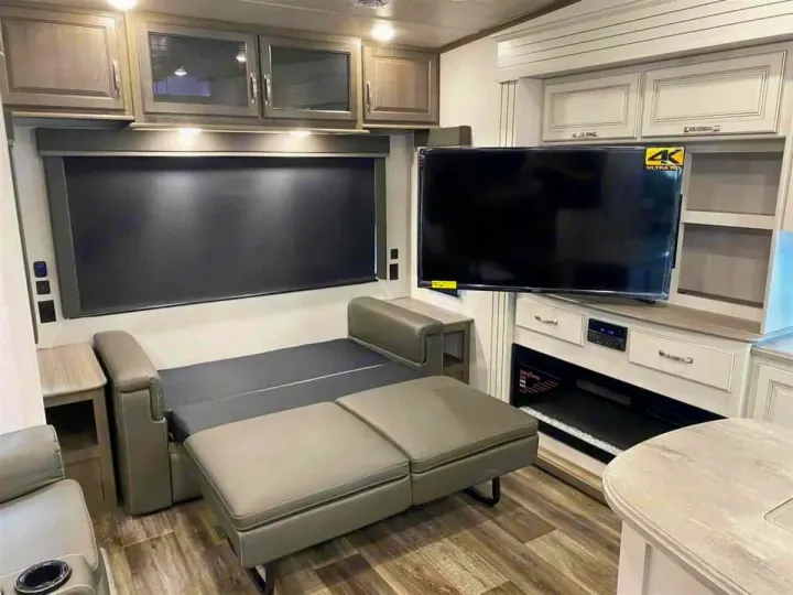 Modern RV rental interior: sofa converts to bed, large TV, fireplace, and sleek cabinets for a cozy living space.. Keystone Cougar 2022